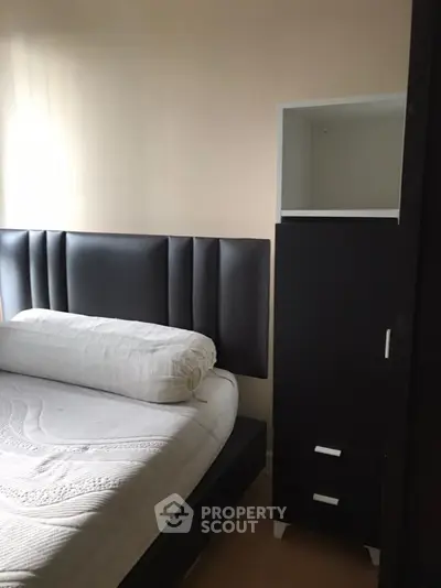 Cozy bedroom with modern black headboard and sleek storage unit, perfect for urban living.
