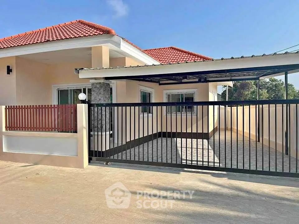 Charming single-story house with red roof and spacious gated driveway.