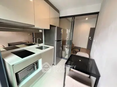 Modern compact kitchen with sleek appliances and dining area in a stylish apartment.