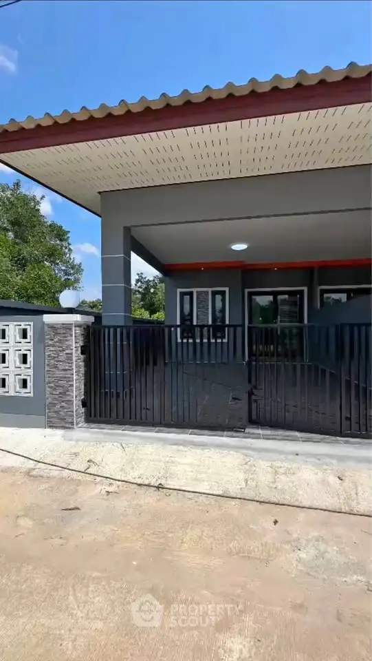 Modern house exterior with gated entrance and spacious driveway.