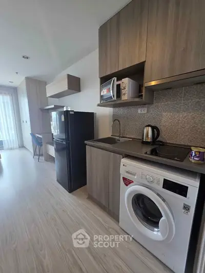 Modern kitchen with sleek appliances and wood cabinetry in a stylish apartment.