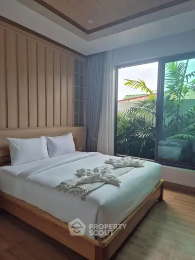 Luxurious bedroom with elegant wooden accents and large window overlooking lush greenery.
