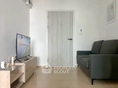 Modern living room with sleek furniture and minimalist decor, featuring a cozy sofa and flat-screen TV.