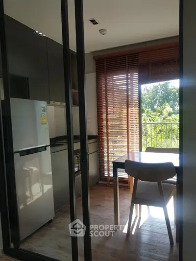Modern kitchen with natural light and balcony view, featuring sleek appliances and wooden accents.