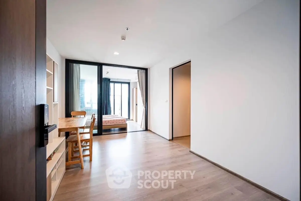 Spacious modern living room with abundant natural light, sleek wooden floors, and direct balcony access, perfect for urban living.