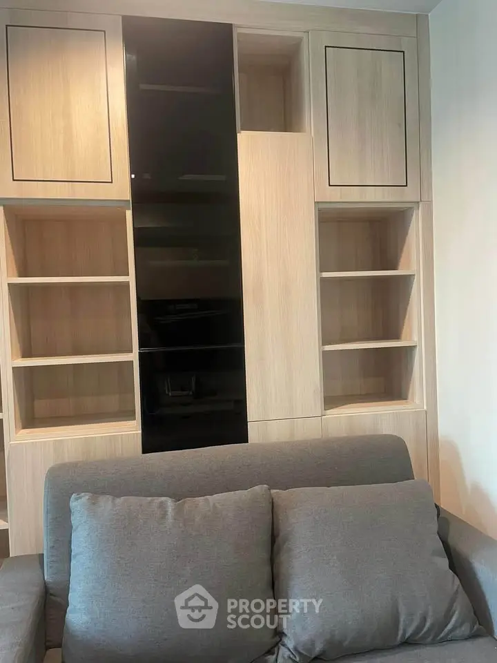 Modern living room with stylish built-in wooden shelves and cozy gray sofa.