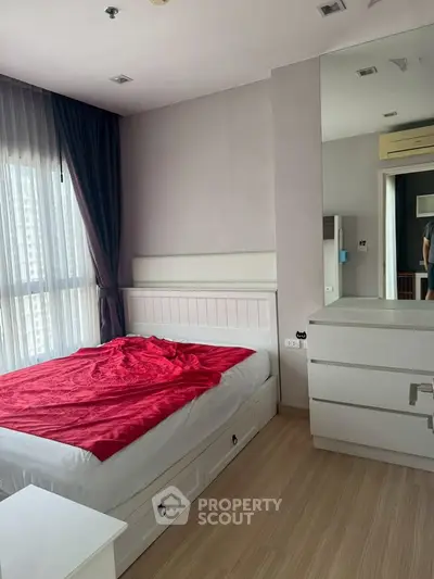 Cozy bedroom with modern decor and large window offering natural light.