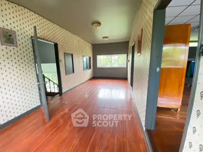 Spacious hallway with wooden flooring and patterned wallpaper, leading to multiple rooms with natural light.