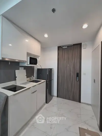 Modern compact kitchen with sleek cabinetry and integrated appliances in a stylish apartment.