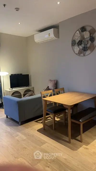 Cozy living room with modern decor and dining area, featuring a stylish air conditioner and wall art.