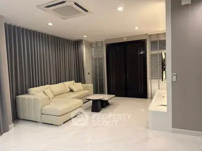 Modern living room with sleek design, featuring a comfortable sectional sofa and elegant marble flooring.