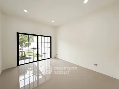 Spacious minimalist room with large windows and garden view, perfect for modern living.