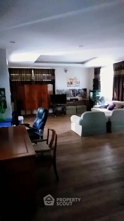 Spacious living room with cozy seating and wooden flooring, perfect for relaxation and entertainment.