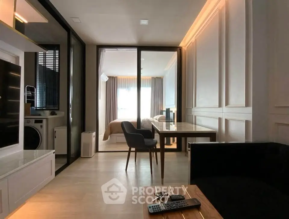 Modern apartment interior with open layout, featuring a cozy living area, dining space, and a glimpse of the bedroom.