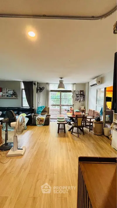 Spacious living room with wooden flooring and large windows offering natural light.