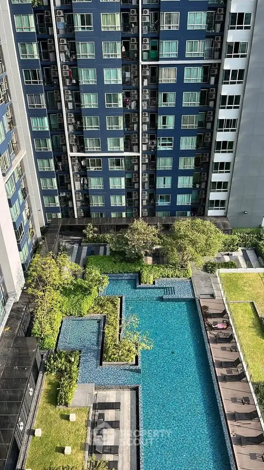 Stunning aerial view of modern apartment building with luxurious swimming pool and lush garden area.