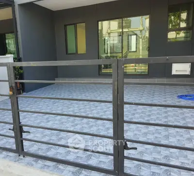 Modern residential building exterior with tiled patio and metal fence