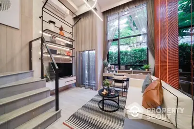 Modern living room with high ceilings, stylish staircase, and large windows offering a lush garden view.