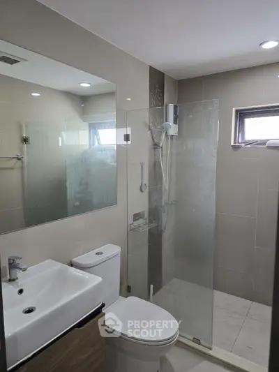 Modern bathroom with glass shower and sleek fixtures in contemporary apartment.