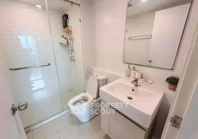 Modern bathroom with glass shower, sleek sink, and toilet in a bright, minimalist design.