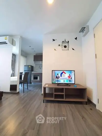 Modern living room with sleek flooring and open kitchen layout in a stylish apartment.