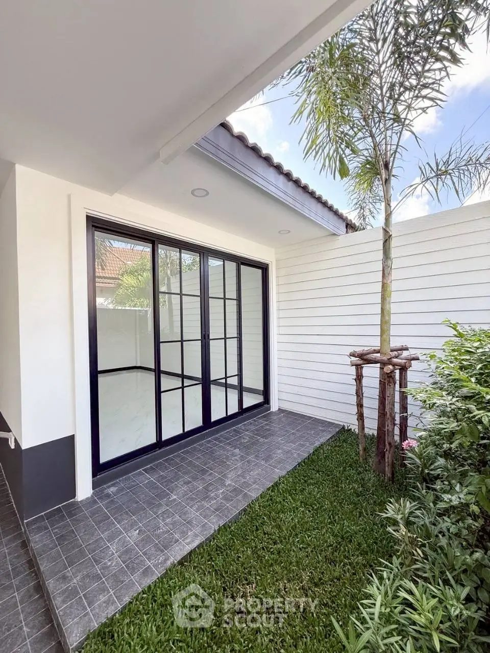 Modern home exterior with sliding glass doors and lush garden space.