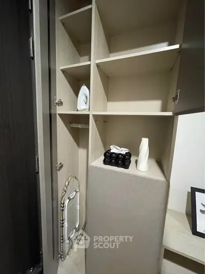Modern storage space with built-in shelves and ironing board in stylish apartment.