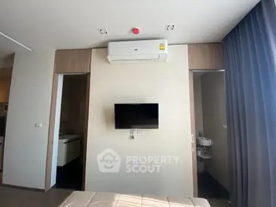 Modern bedroom with wall-mounted TV and air conditioning, featuring sleek design and natural lighting.