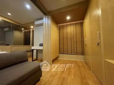 Modern living room with wooden flooring and built-in storage, featuring a cozy sofa and ambient lighting.