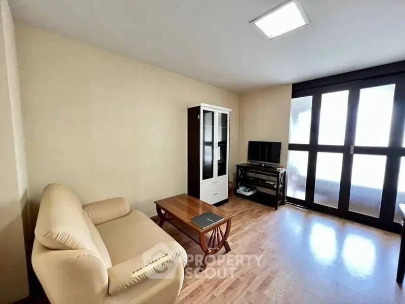 Cozy living room with natural light, wooden flooring, and modern furniture.