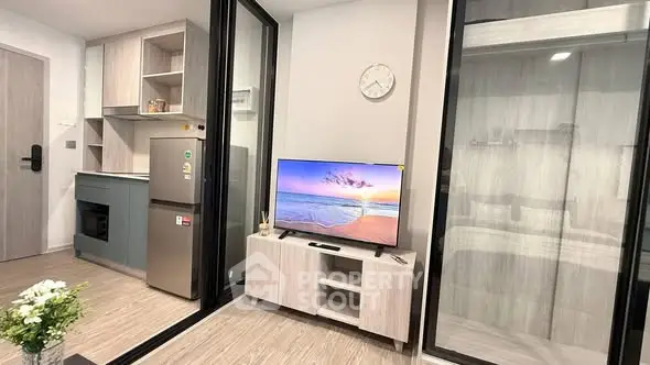 Modern apartment interior with sleek kitchen and cozy living area featuring a flat-screen TV.