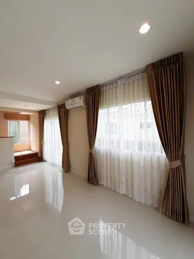 Spacious living room with large windows and elegant curtains