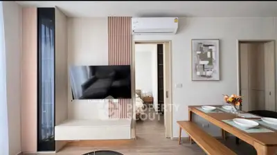 Modern living room with sleek design, wall-mounted TV, and dining area in a stylish apartment.