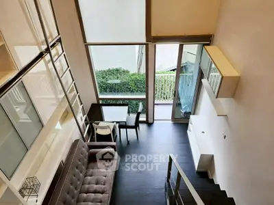 Modern loft apartment with high ceilings and large windows, featuring a stylish living area and dining space.