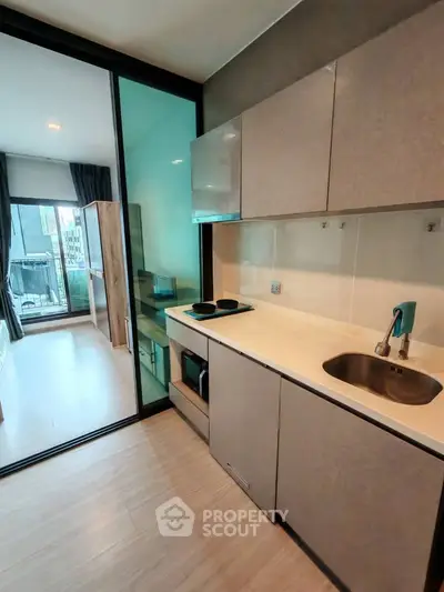 Modern kitchen with sleek cabinetry and open layout leading to a bright living area with balcony view.