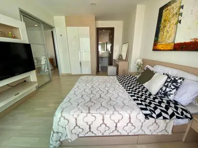 Spacious modern bedroom with stylish decor and large TV, perfect for relaxation.