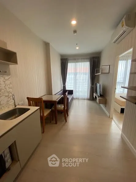 Modern open-plan living room with kitchen and dining area, featuring sleek design and natural light.
