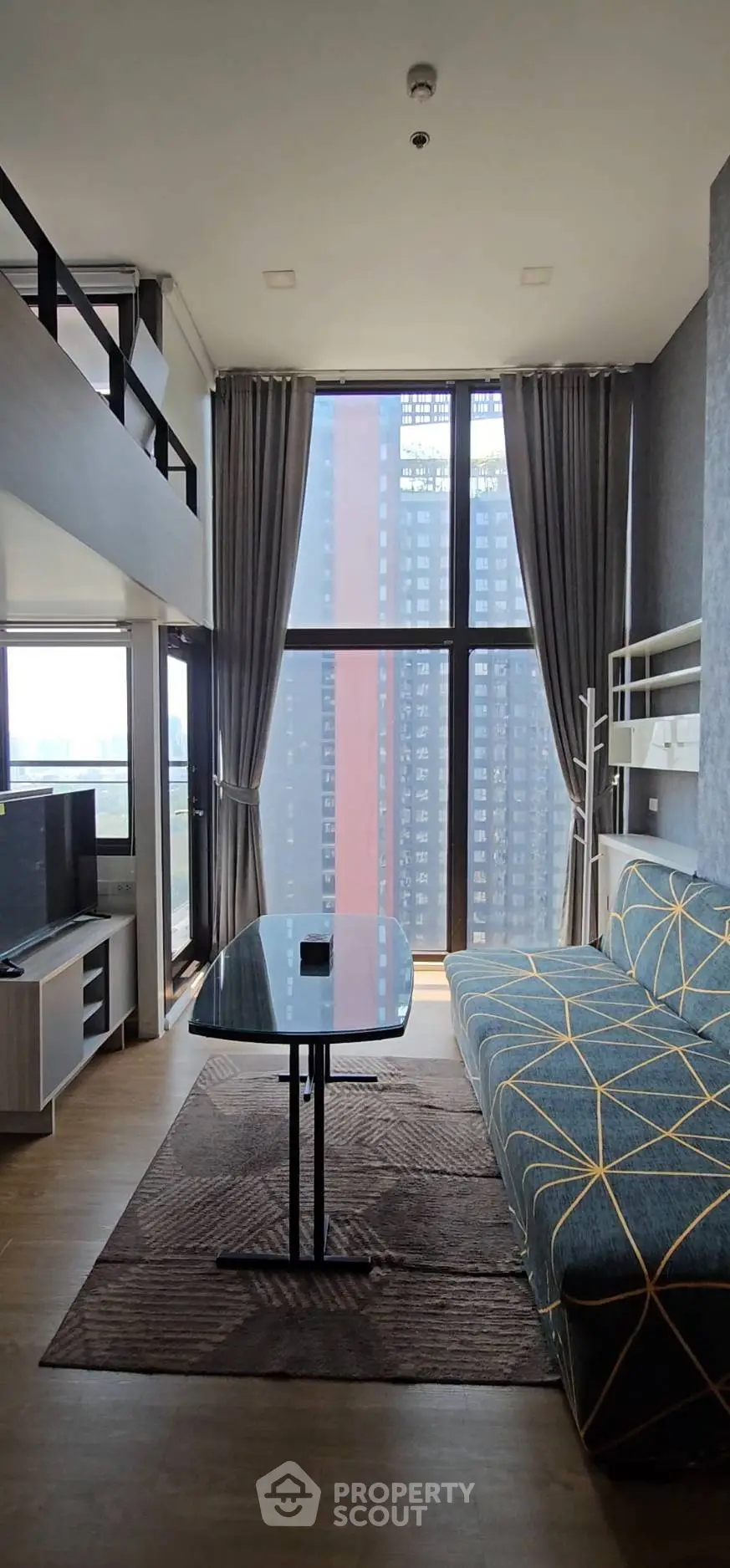 Modern living room with high ceilings and large windows offering city views in a stylish apartment.