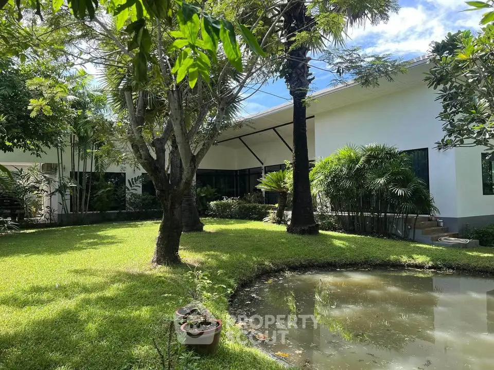 Stunning garden view with lush greenery and serene pond in modern property.