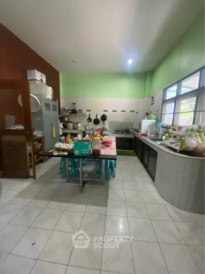 Spacious kitchen with tiled floor, ample counter space, and large windows for natural light.