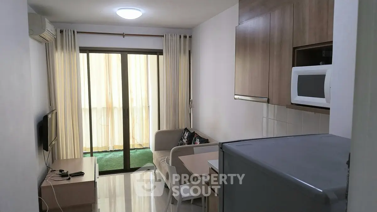 Cozy apartment living room with modern kitchen and balcony view.