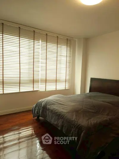 Cozy bedroom with wooden blinds and polished hardwood floors