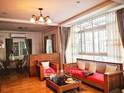 Charming living room with elegant wooden furniture and large windows for natural light.