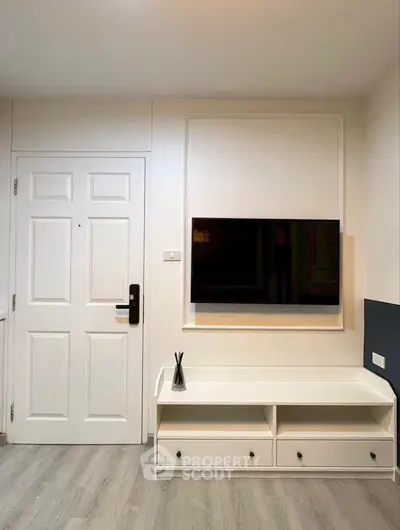 Modern apartment entrance with sleek TV setup and stylish storage unit.