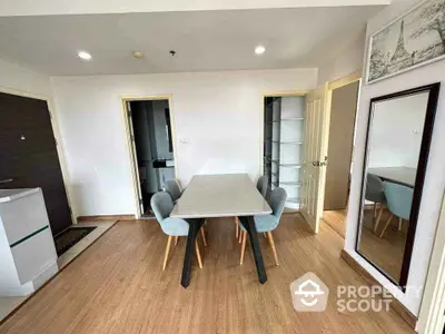 Modern dining area with stylish table and chairs, wooden flooring, and wall mirror in a cozy apartment.