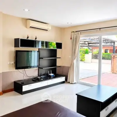 Modern living room with sleek entertainment unit and sliding glass doors to patio.