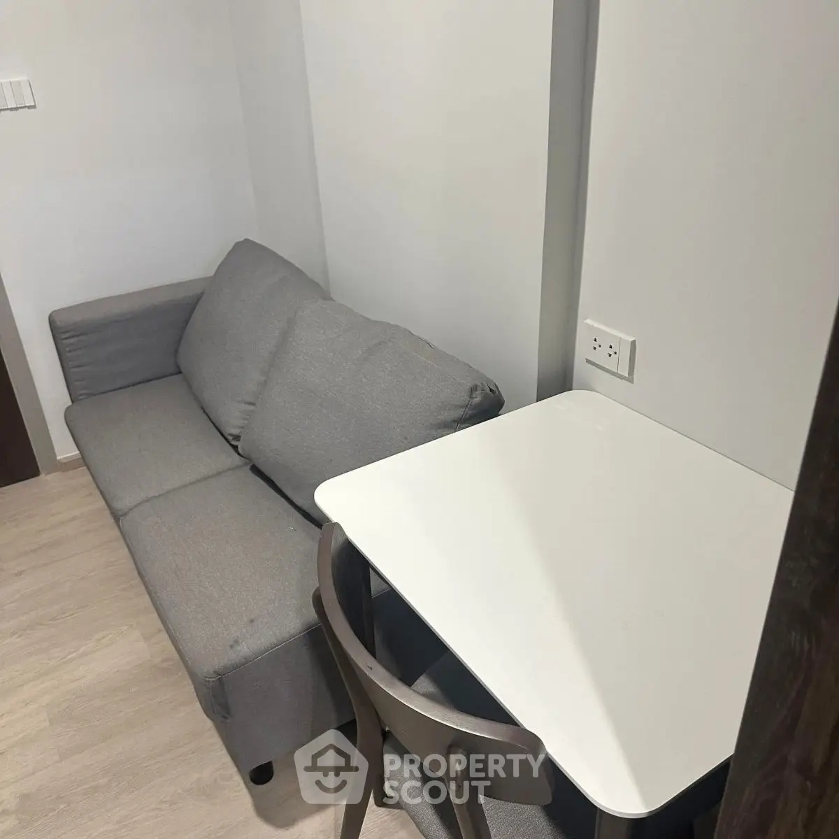 Cozy compact living area with a gray sofa and a small white table, perfect for urban living.