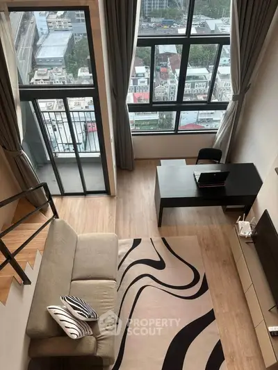 Modern loft apartment with large windows and city view, featuring stylish living area and workspace.