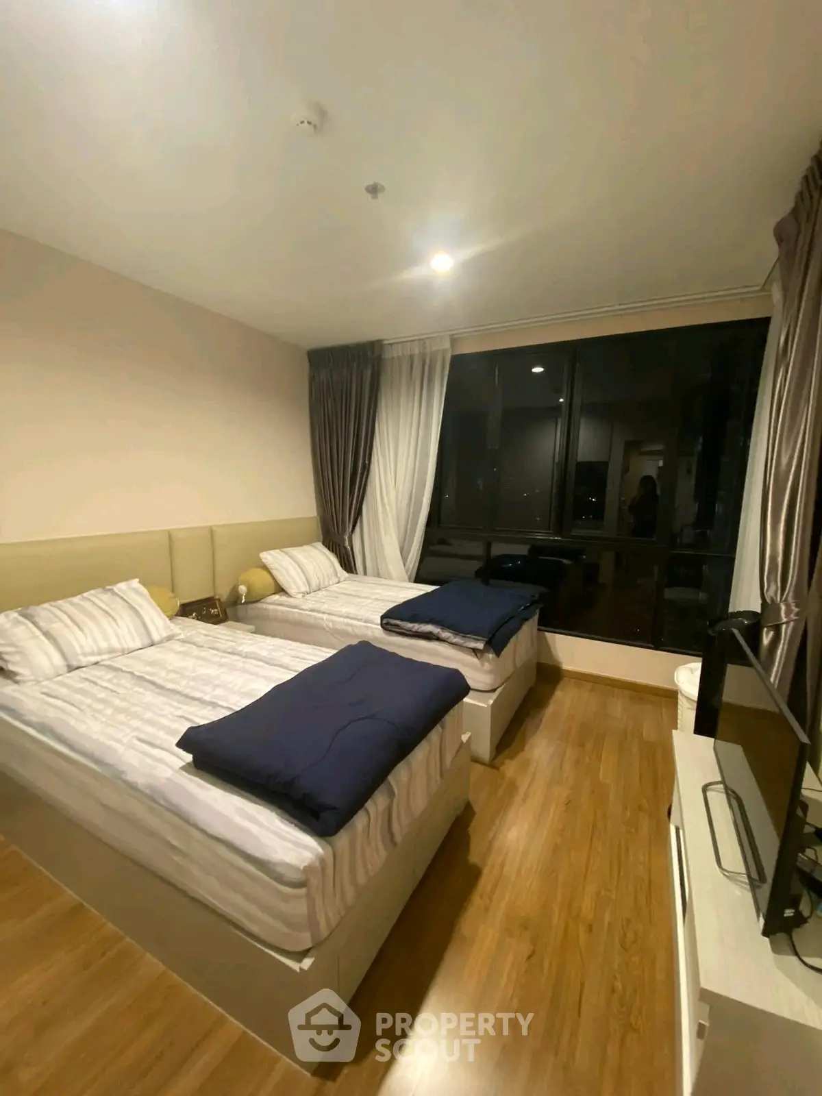 Spacious bedroom with twin beds and large window offering city view