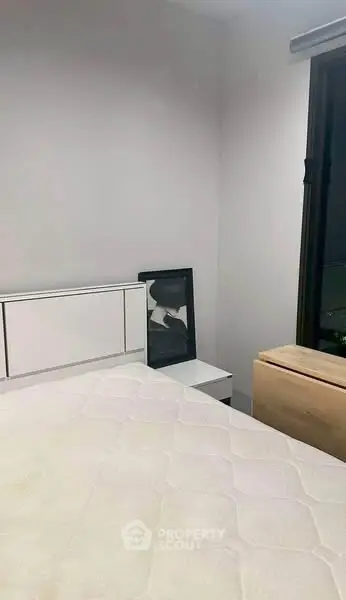Cozy bedroom with minimalist decor and large window for natural light.